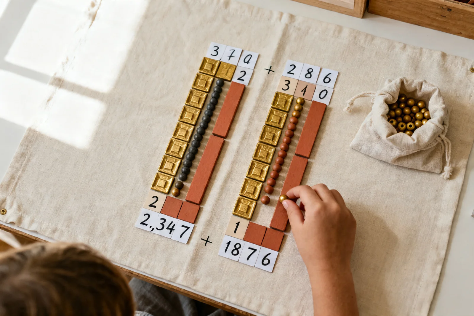Banková hra v priebehu — 2 347 + 1 876 rozložené v perlách a číselných kartách, kým dieťa vymieňa jednotky za desiatku